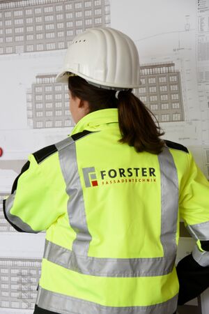 Projektleiter steht vor einem an die Wand gepinnten Bauplan